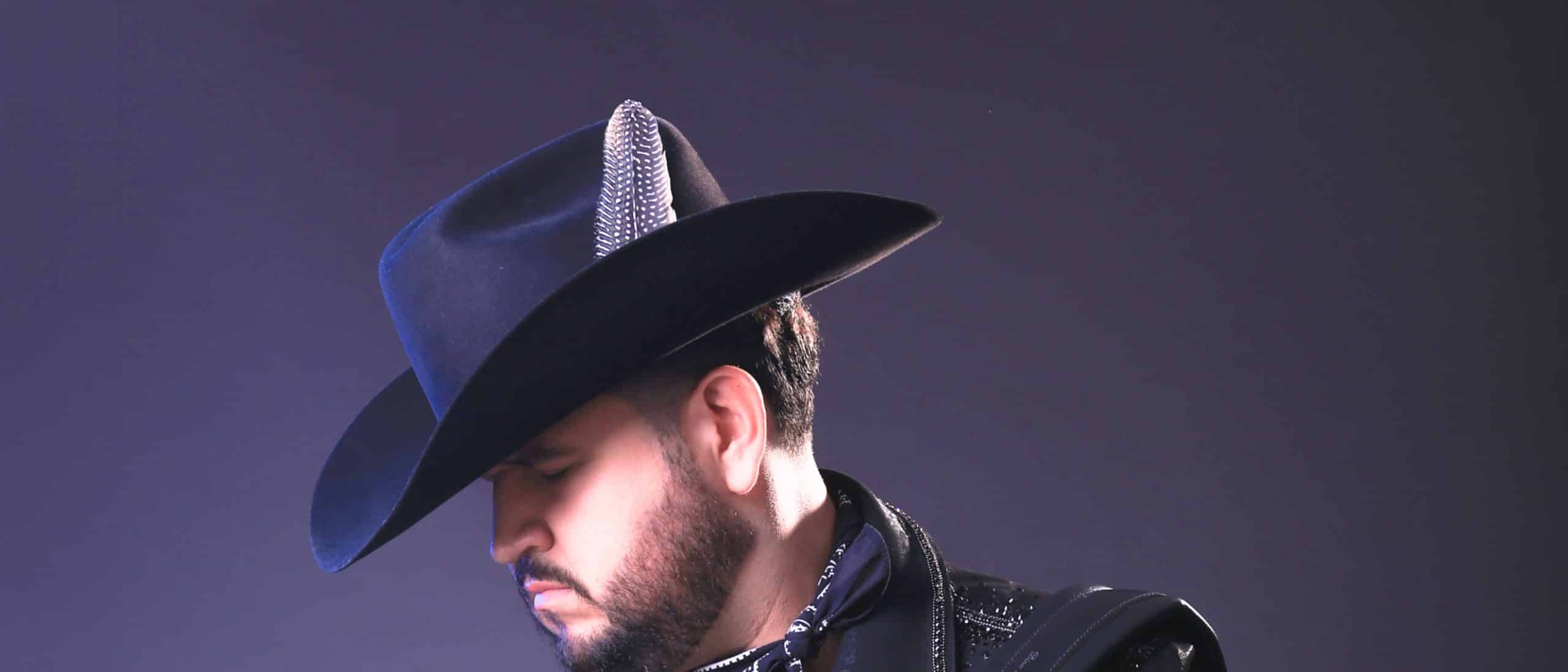 Edén Muñoz de perfil con sombrero negro y detalle de pluma, imagen artística ideal para contratación de shows y eventos en vivo